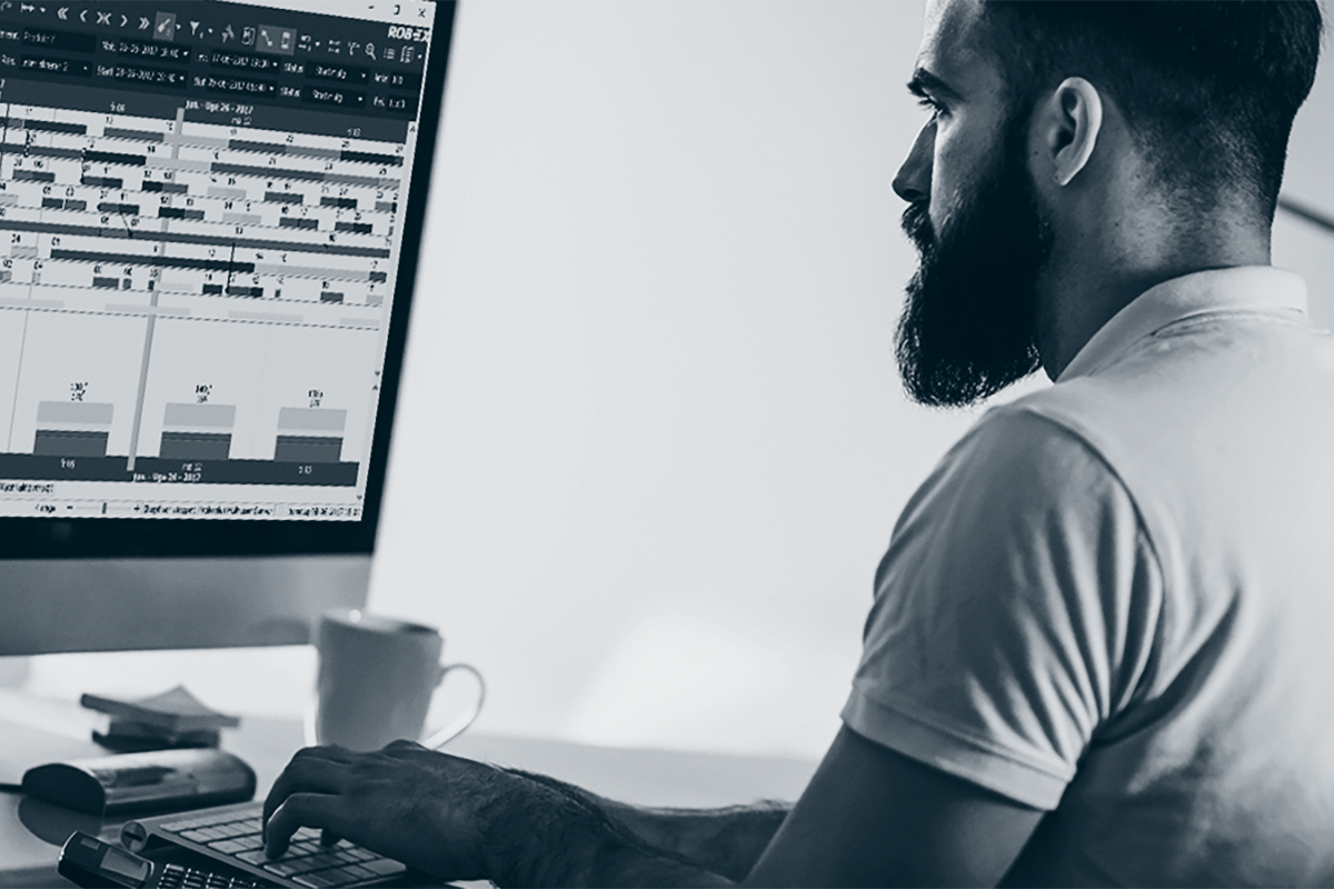 Mann sitter foran PC for produksjonsplanlegging.